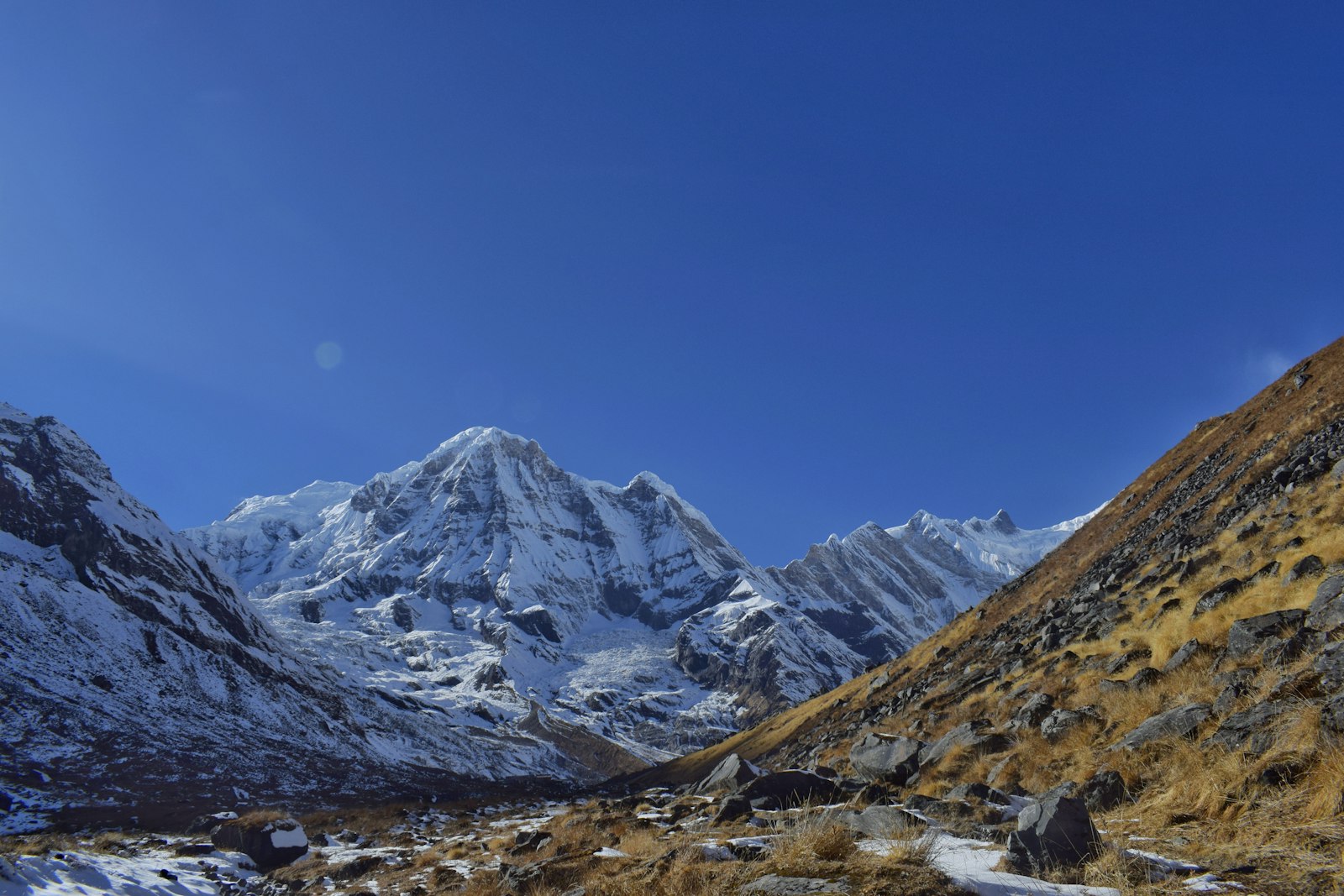 The Annapurna Sanctuary valley with snow peaks and a golden grass slope