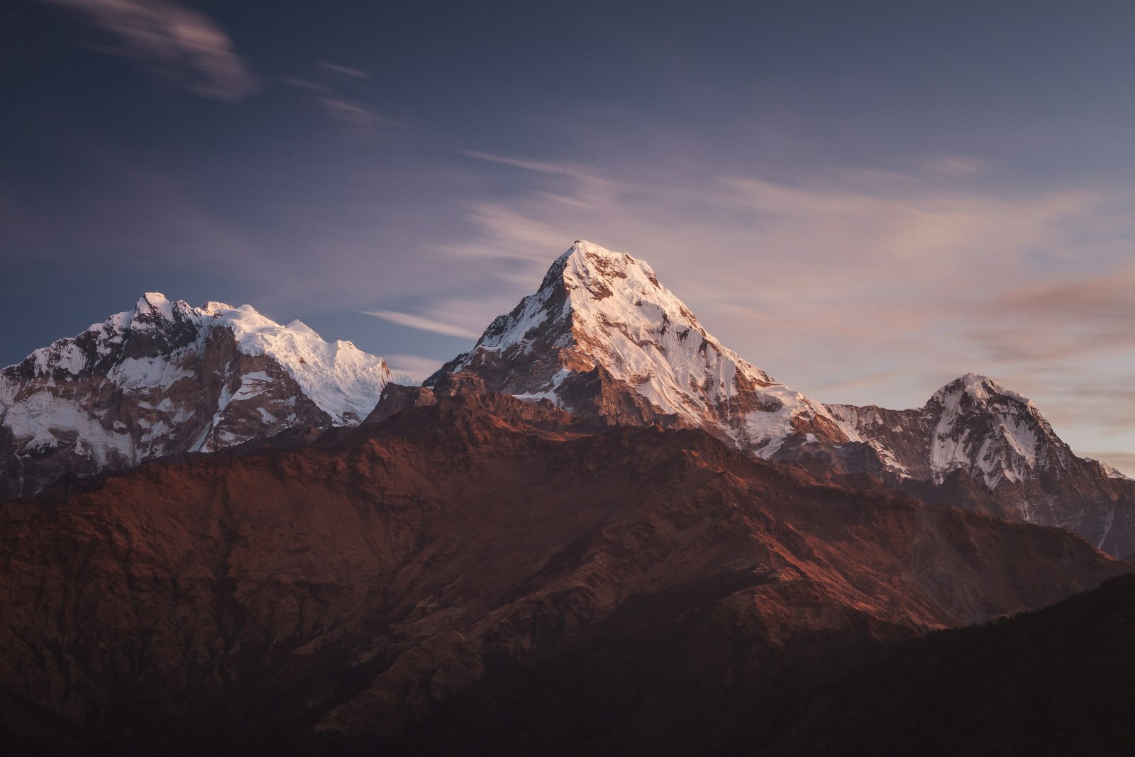 The Annapurna South massif glowing at sunrise above forested ridges